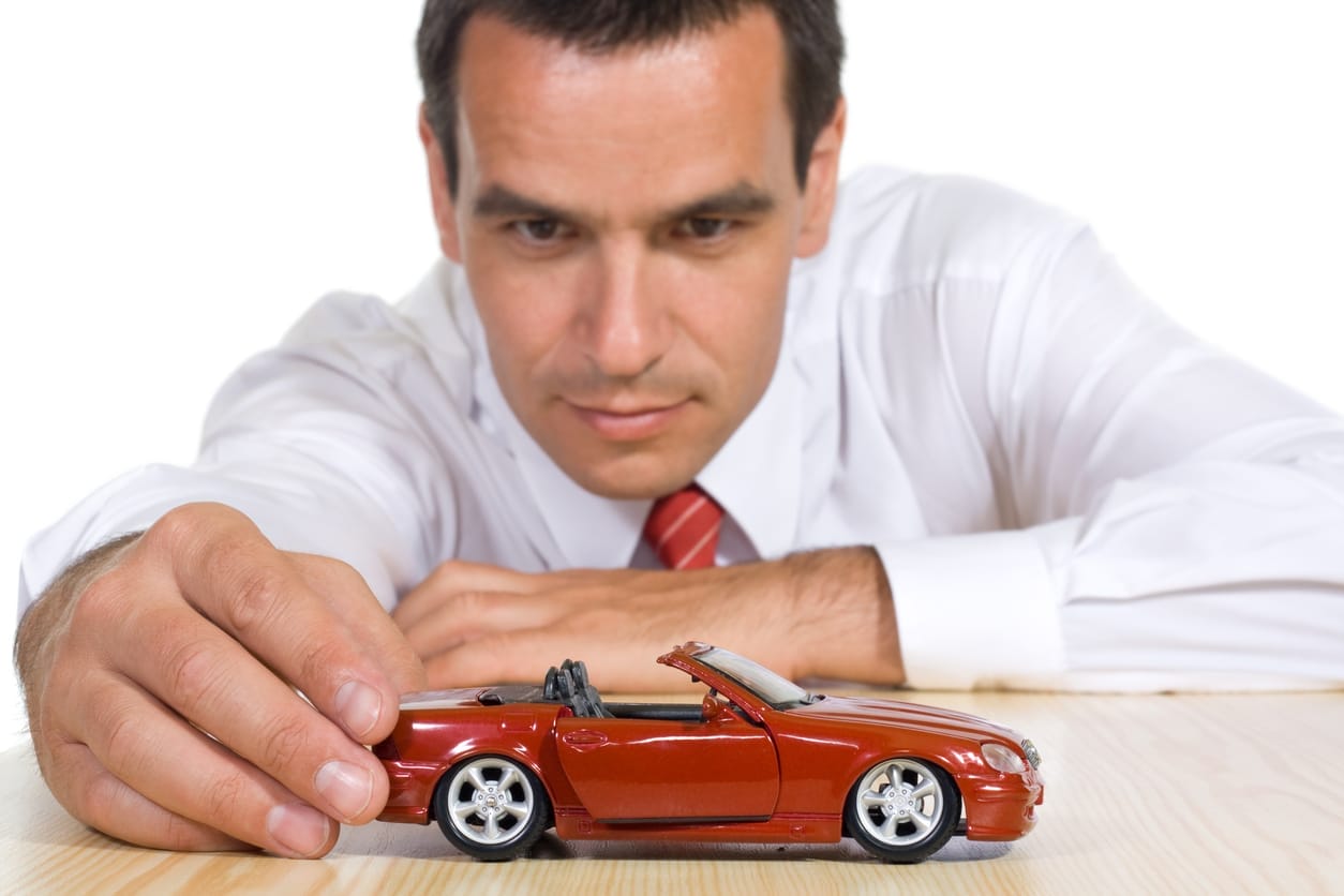 Man playing with red diecast model car.