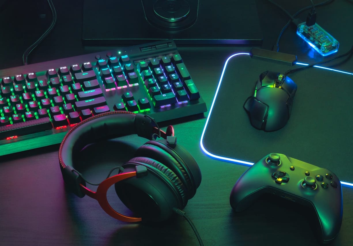 Gaming gear, mouse, keyboard, joystick, headset, mobile joystick, in ear headphone and mouse pad on black table background.