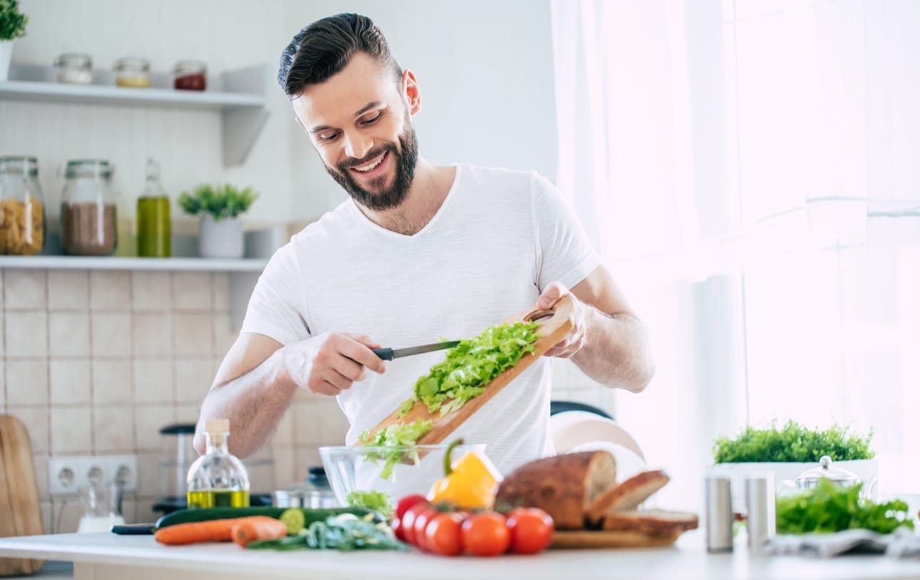 Young man preparing a salad at home.
